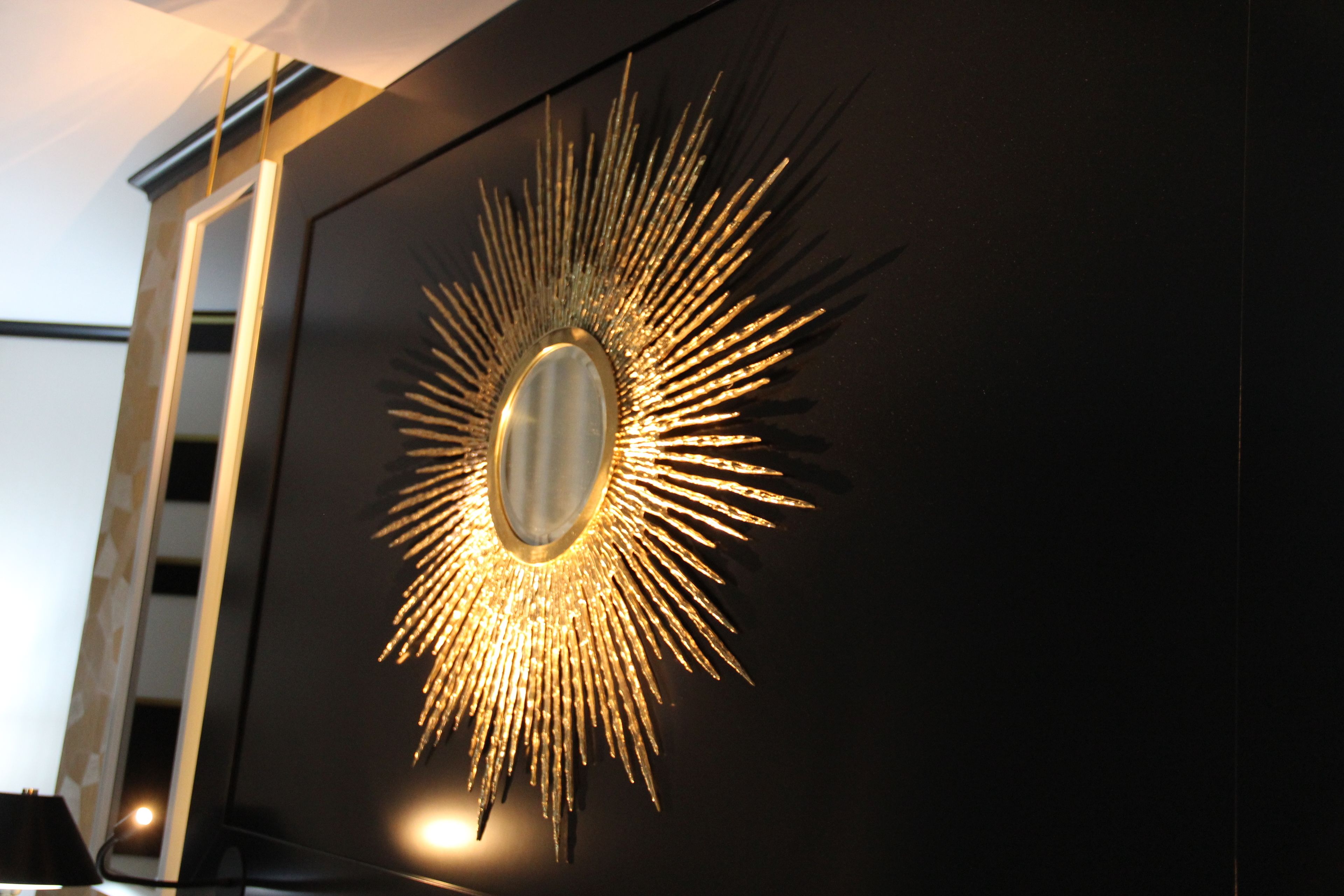 A wall-mounted mirror with a sunburst design.