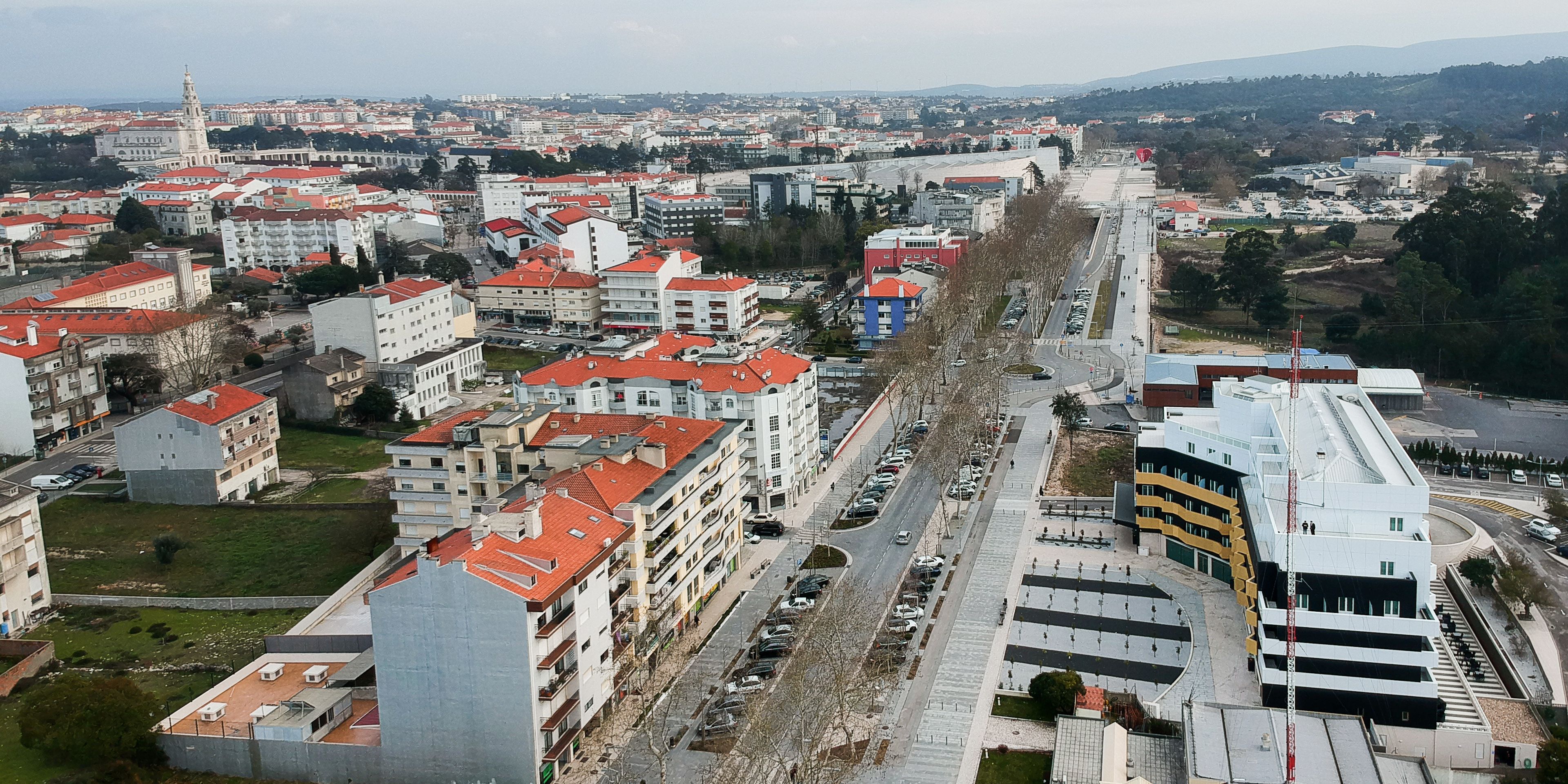 Un paisaje urbano con una torre destacada, una avenida amplia y varios edificios.