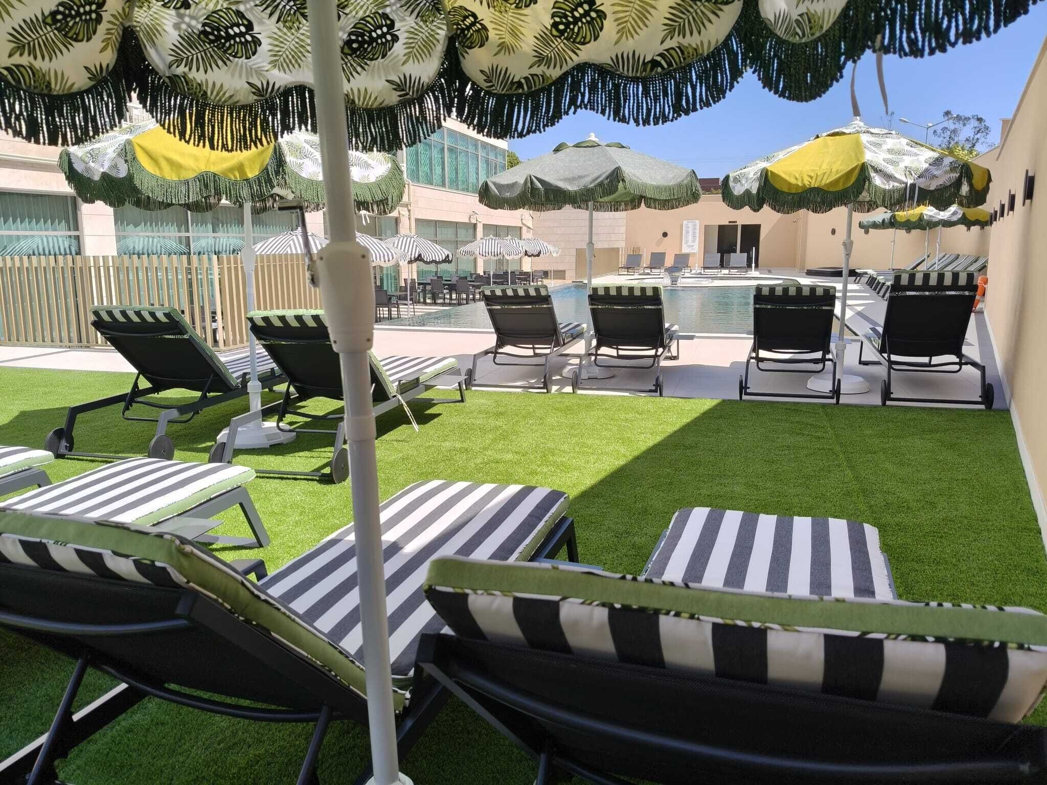 A poolside area with sun loungers, umbrellas, and a clear view of the pool.