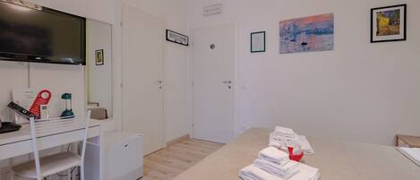 Habitación de hotel con cama, escritorio con ordenador, televisión y obras de arte en las paredes.
