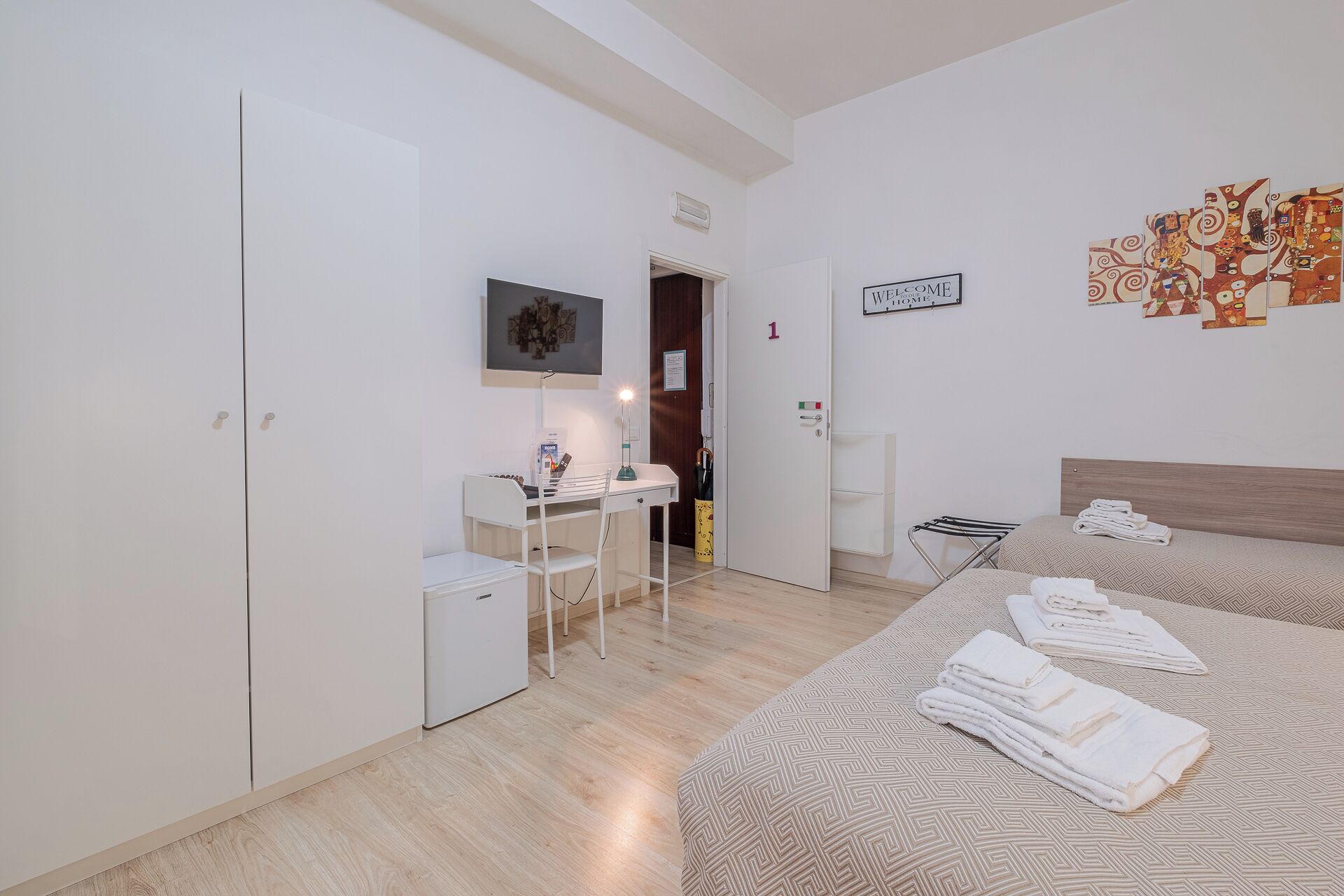 Una camera da letto con due letti, una scrivania, un armadio e una porta contrassegnata dal numero 1.