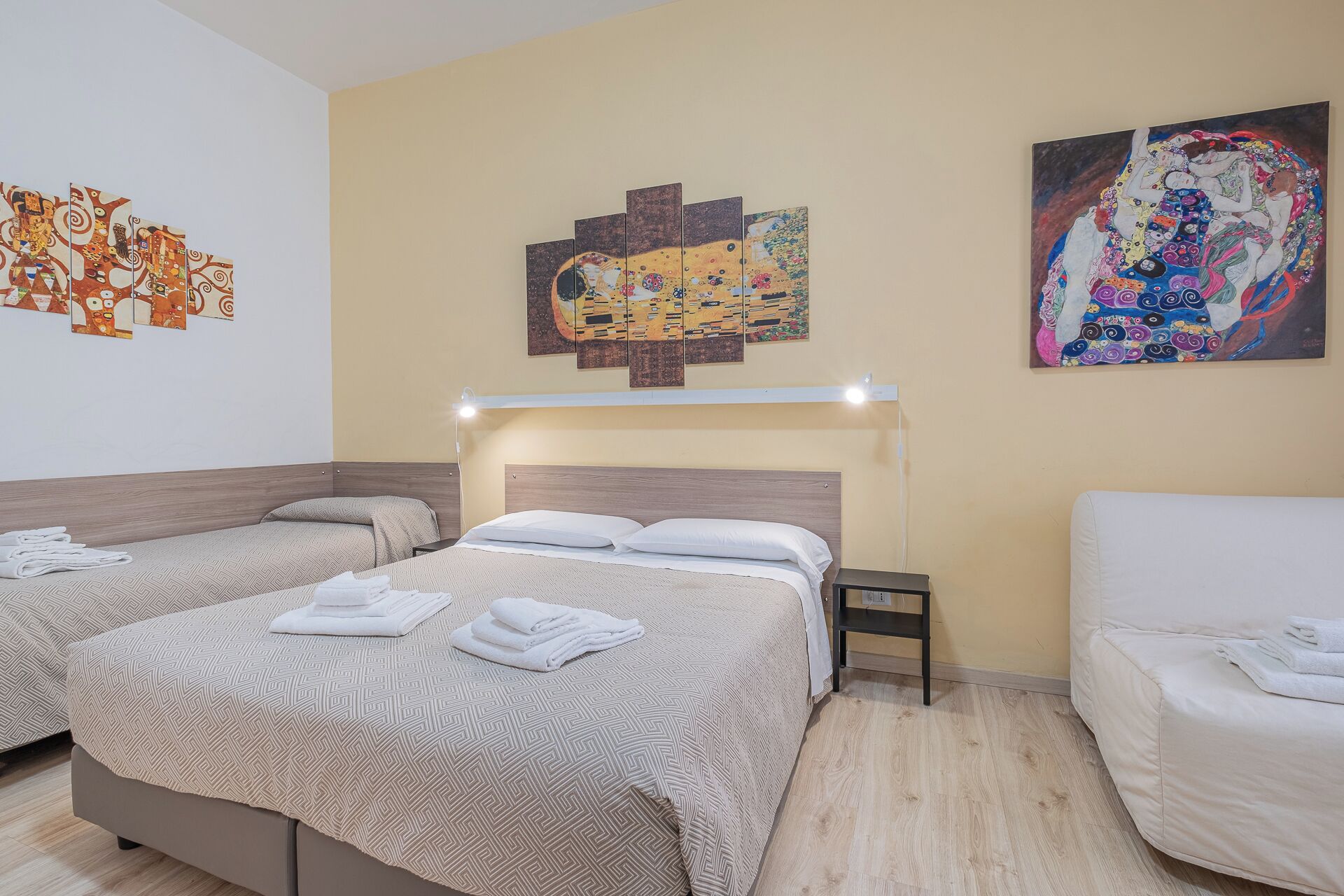Une chambre d’hôtel avec deux lits, une table de chevet et des œuvres d’art accrochées aux murs.