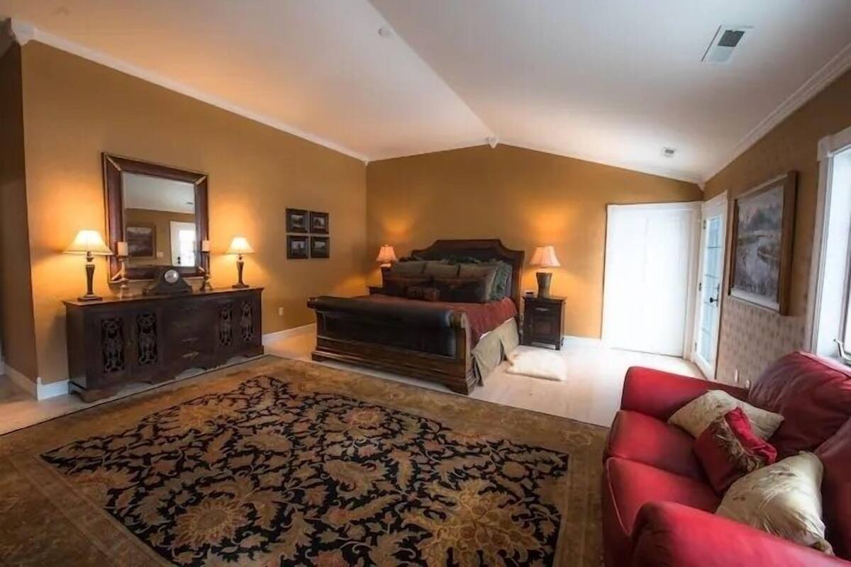 A bedroom with a bed, dresser, and a red couch.