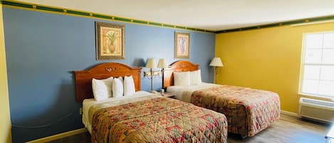 Habitación de hotel con dos camas, cabecero de madera, mesita de noche, lámpara y ventana.