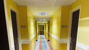 A hallway with yellow walls, doors numbered 101 and 102, and a striped floor. - Mountain Inn & Suites Dunlap (Dunlap)