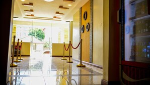 Un vestíbulo de hotel con piso pulido, una recepción y un separador de vidrio con un objeto decorativo.