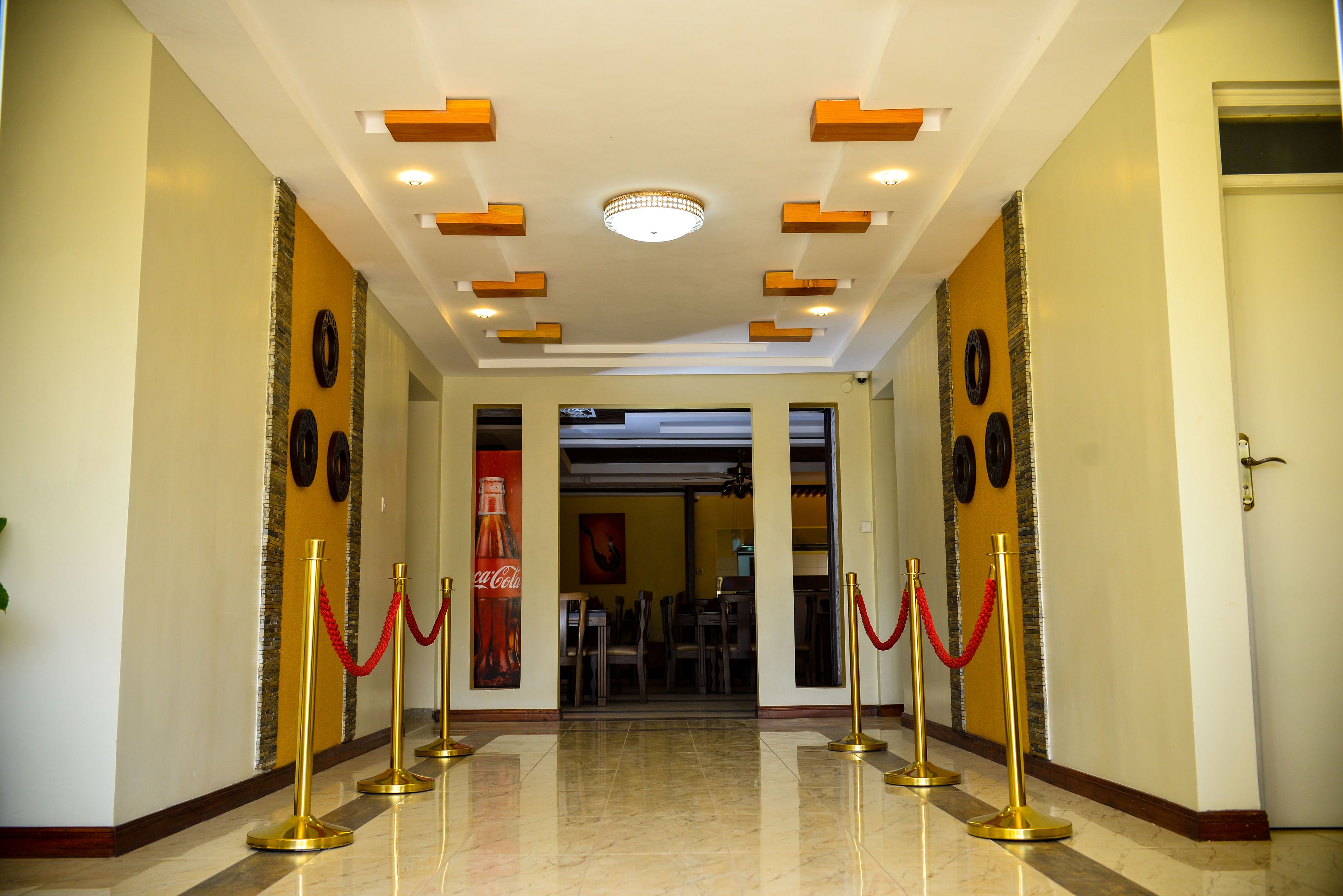 A hotel lobby with a marble floor, red ropes, and gold stanchions.