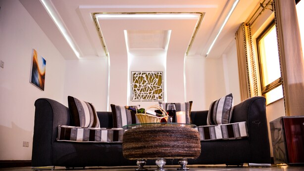 Una sala de estar moderna con un sofá, una mesita de centro de vidrio y un elemento decorativo en la pared.