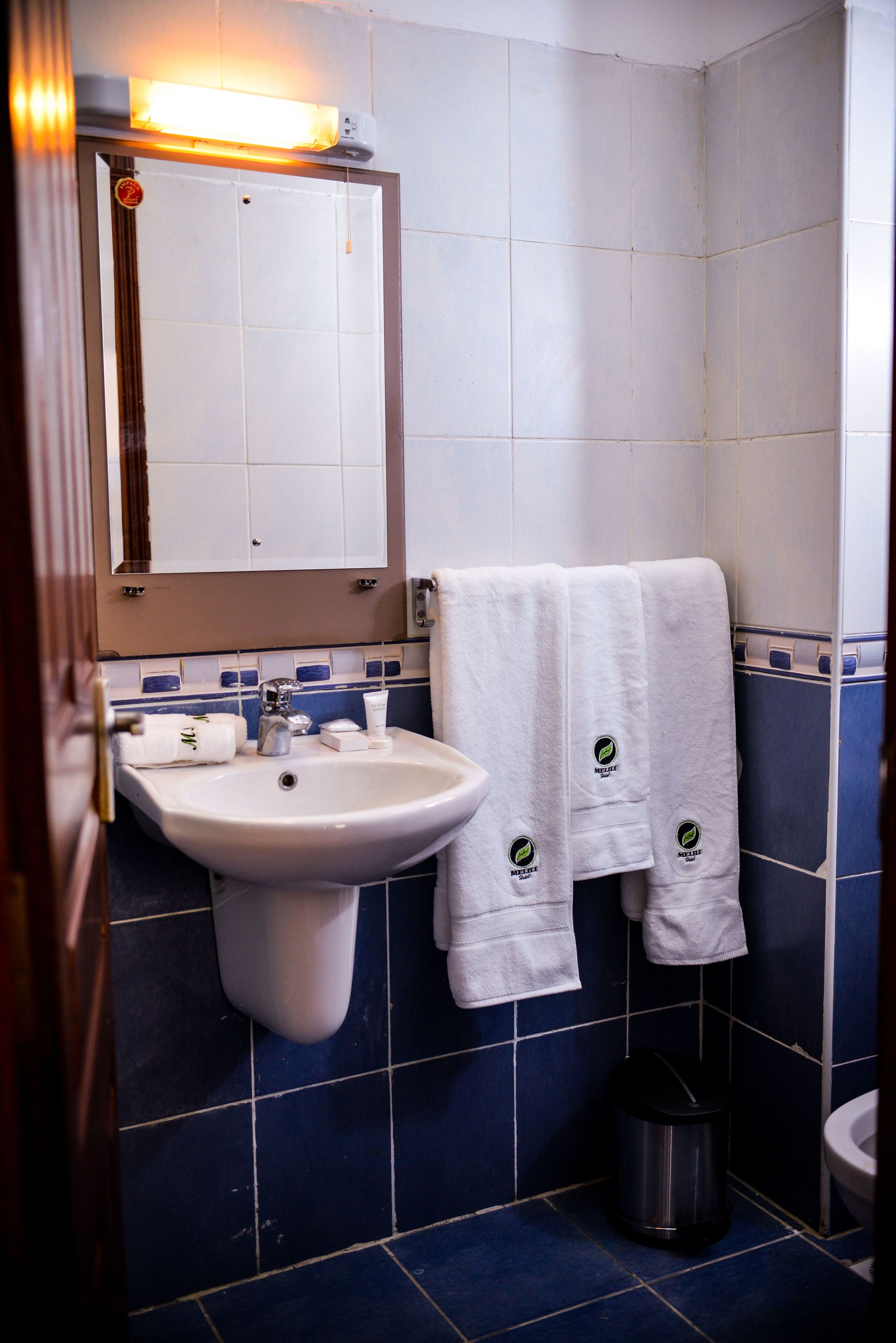 A bathroom with a sink, mirror, and two towels hanging on the wall.