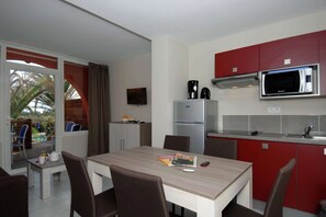 Eine kompakte Küche mit Mikrowelle, Kühlschrank und einem Essbereich mit Tisch und Stühlen.