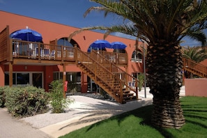Un hôtel à la façade rouge, doté de balcons en bois et de parasols bleus.