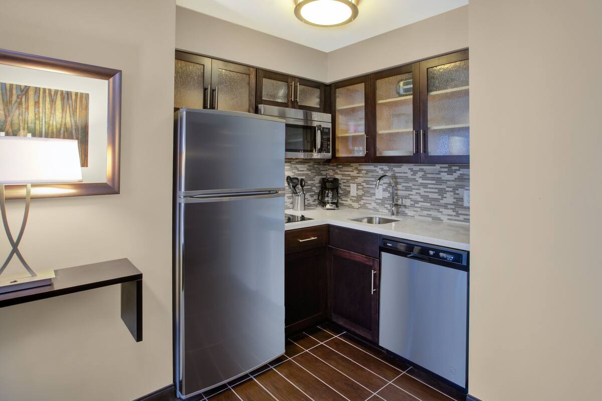 A compact kitchen with a refrigerator, microwave, and dishwasher.