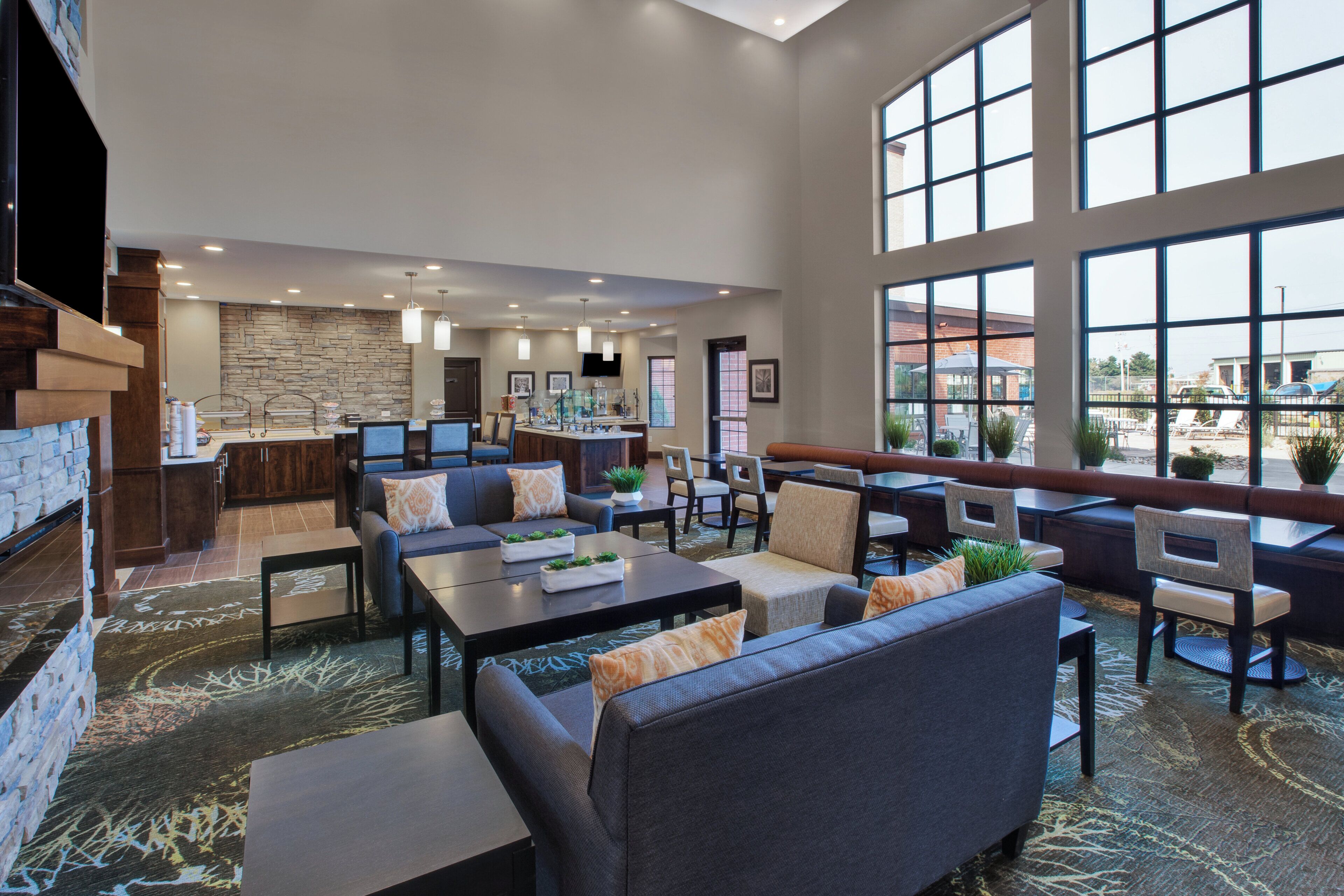 A spacious indoor area with a stone wall, seating arrangements, and large windows.