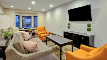 A modern living room with a sofa, armchairs, a coffee table, and a flat-screen TV mounted on the wall.