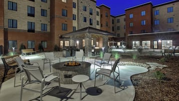 An outdoor patio area with a fire pit, seating, and a covered seating area.