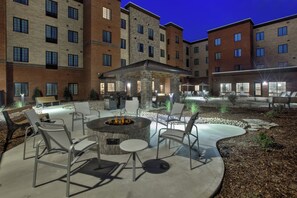 An outdoor patio area with a fire pit, seating, and a covered seating area.