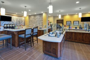 A modern breakfast bar with seating, a coffee station, and a stone accent wall. - Staybridge Suites Benton Harbor - St. Joseph by IHG (Benton Harbor)