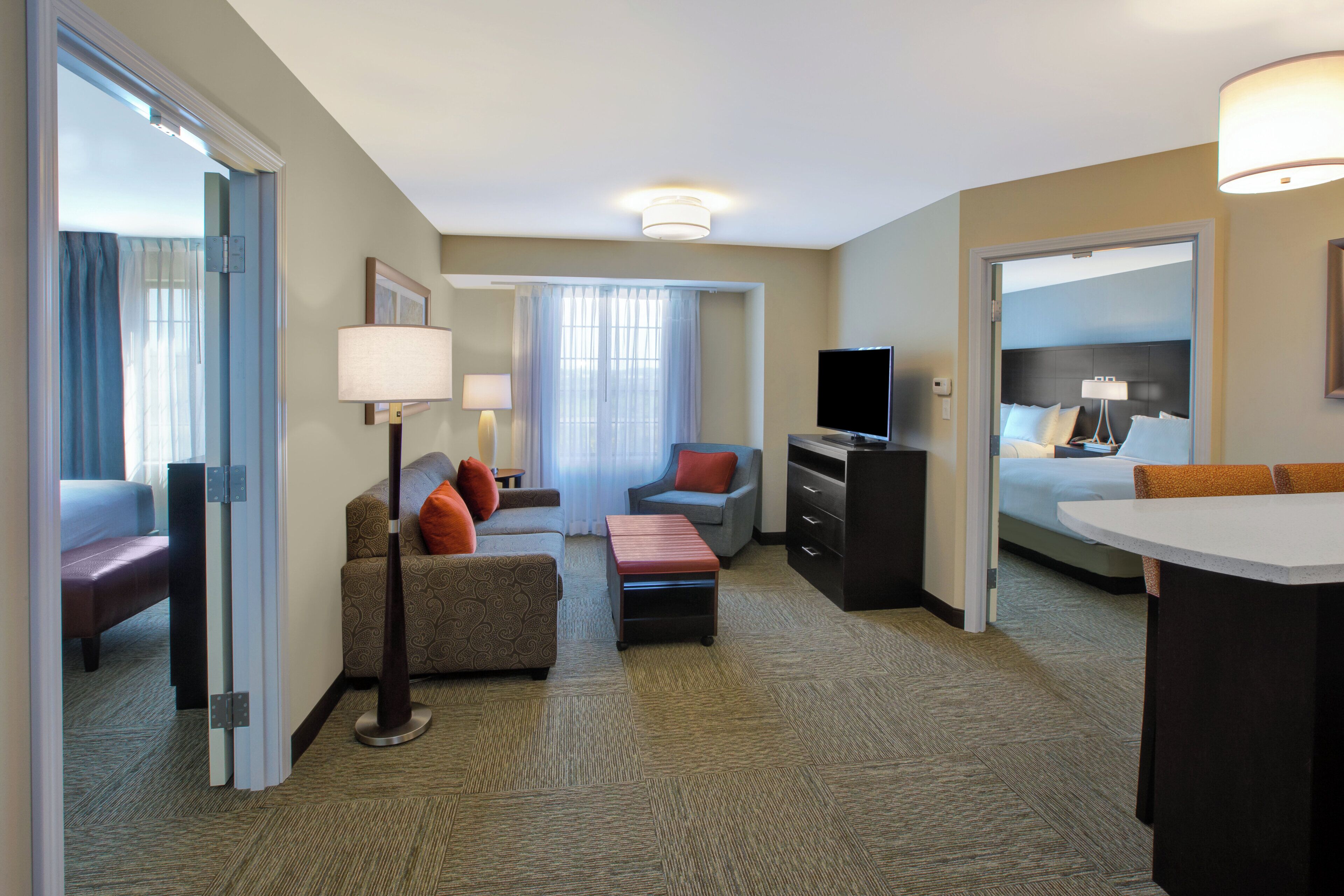 A hotel room with a sofa, a desk, a television, and a bed.