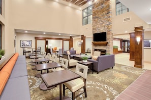 A spacious indoor area with multiple seating arrangements, including sofas and tables, and a fireplace.