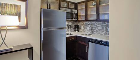 A compact kitchen with a stainless steel refrigerator, a microwave, and a dishwasher.