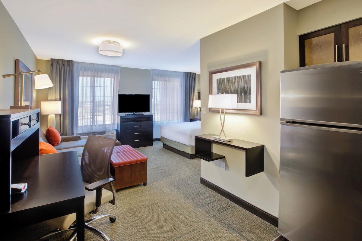 Une chambre d’hôtel équipée d’un lit, d’un bureau, d’une chaise, d’une télévision et d’un réfrigérateur.