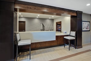 A reception area with a counter, two chairs, a door, and a framed picture on the wall. - Staybridge Suites Benton Harbor - St. Joseph by IHG (Benton Harbor)