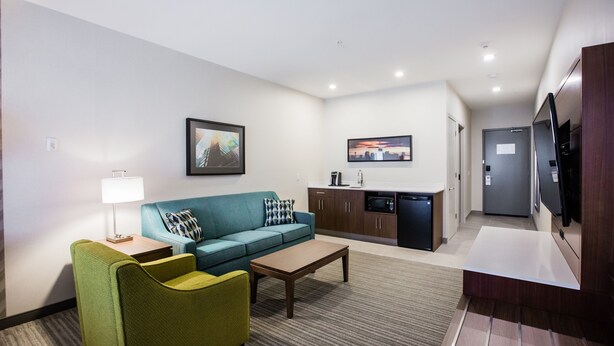 A modern hotel room with a living area, kitchenette, and a flat-screen TV. - Holiday Inn Calgary South Conference Center by IHG (Calgary)