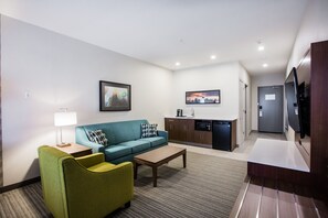A modern hotel room with a living area, kitchenette, and a flat-screen TV. - Holiday Inn Calgary South Conference Center by IHG (Calgary)