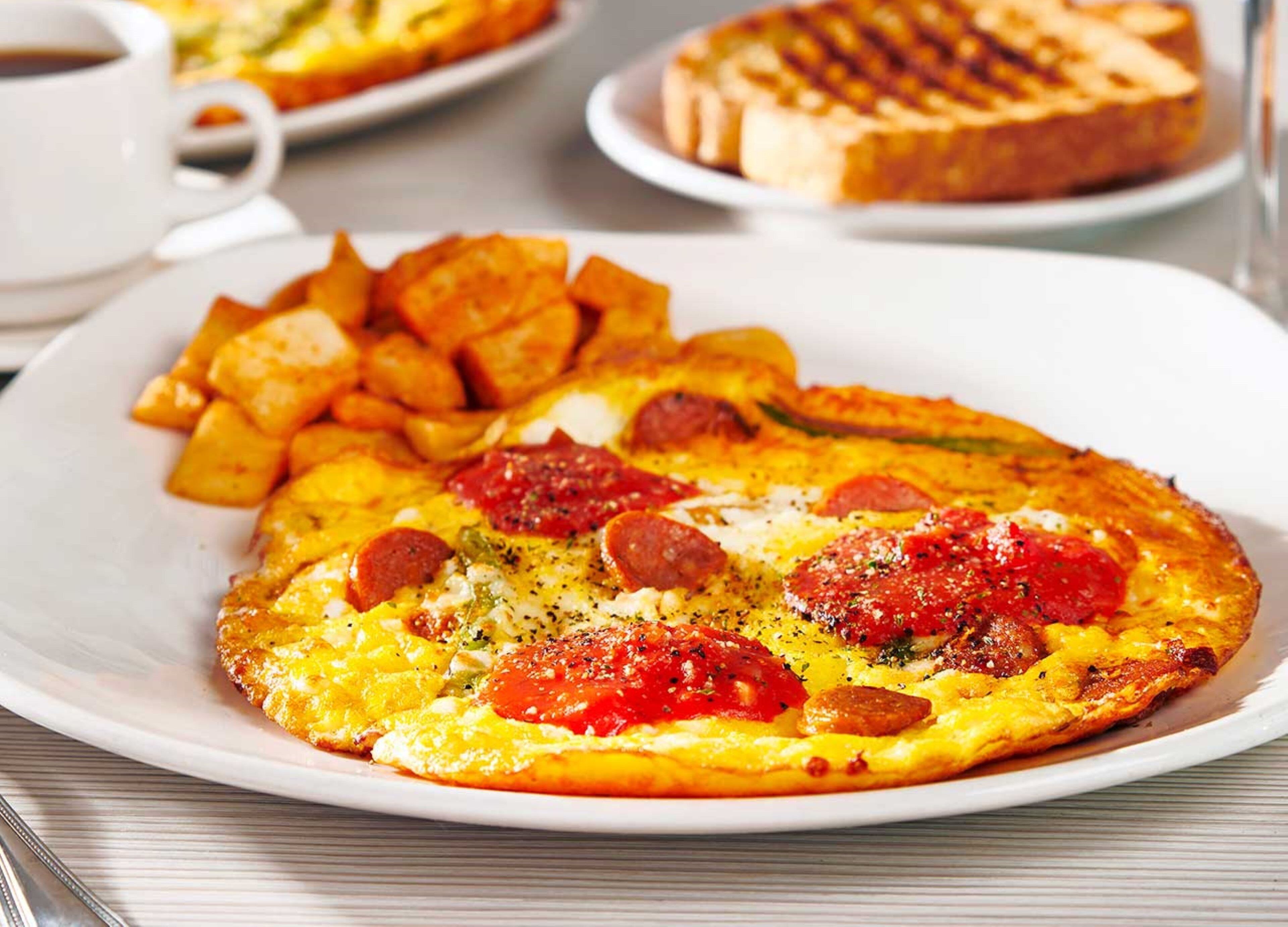 A breakfast plate with eggs, tomatoes, and pepperoni, accompanied by hash browns and toast.