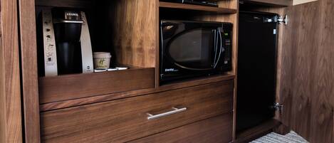 A kitchenette with a microwave, coffee maker, and a refrigerator.