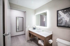 A modern bathroom with a white sink, a large mirror, and a toilet.