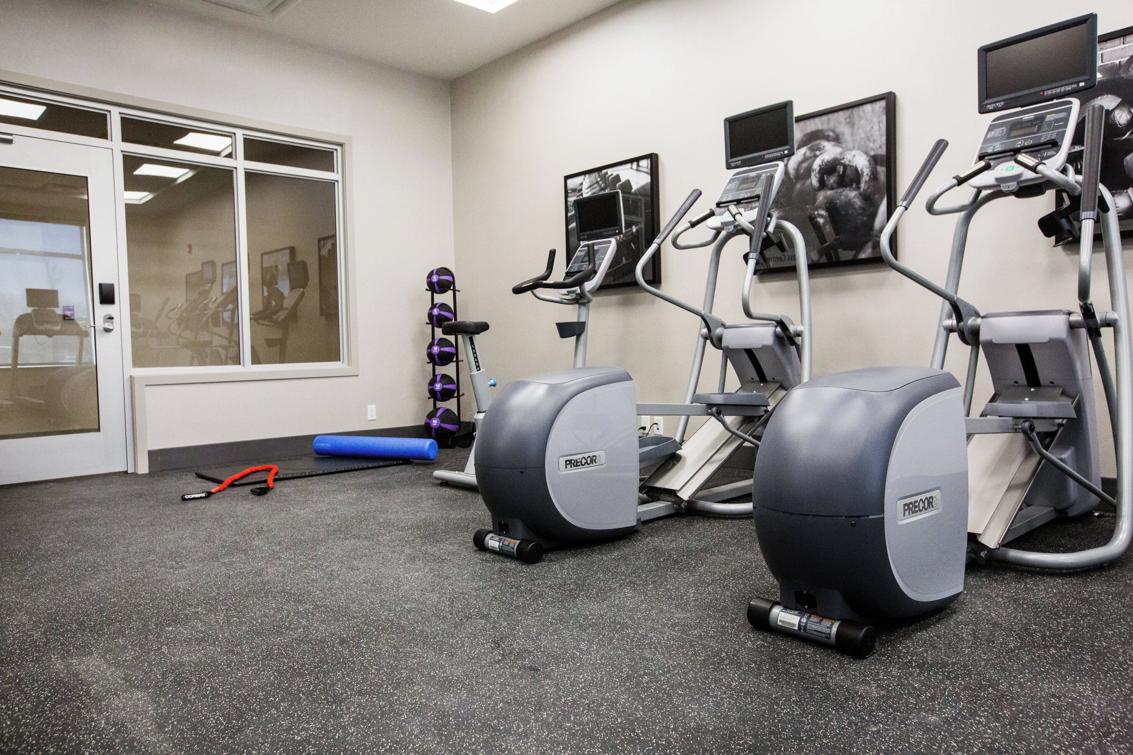 Un gimnasio con cintas de correr, bicicletas estáticas y pelotas de ejercicio.