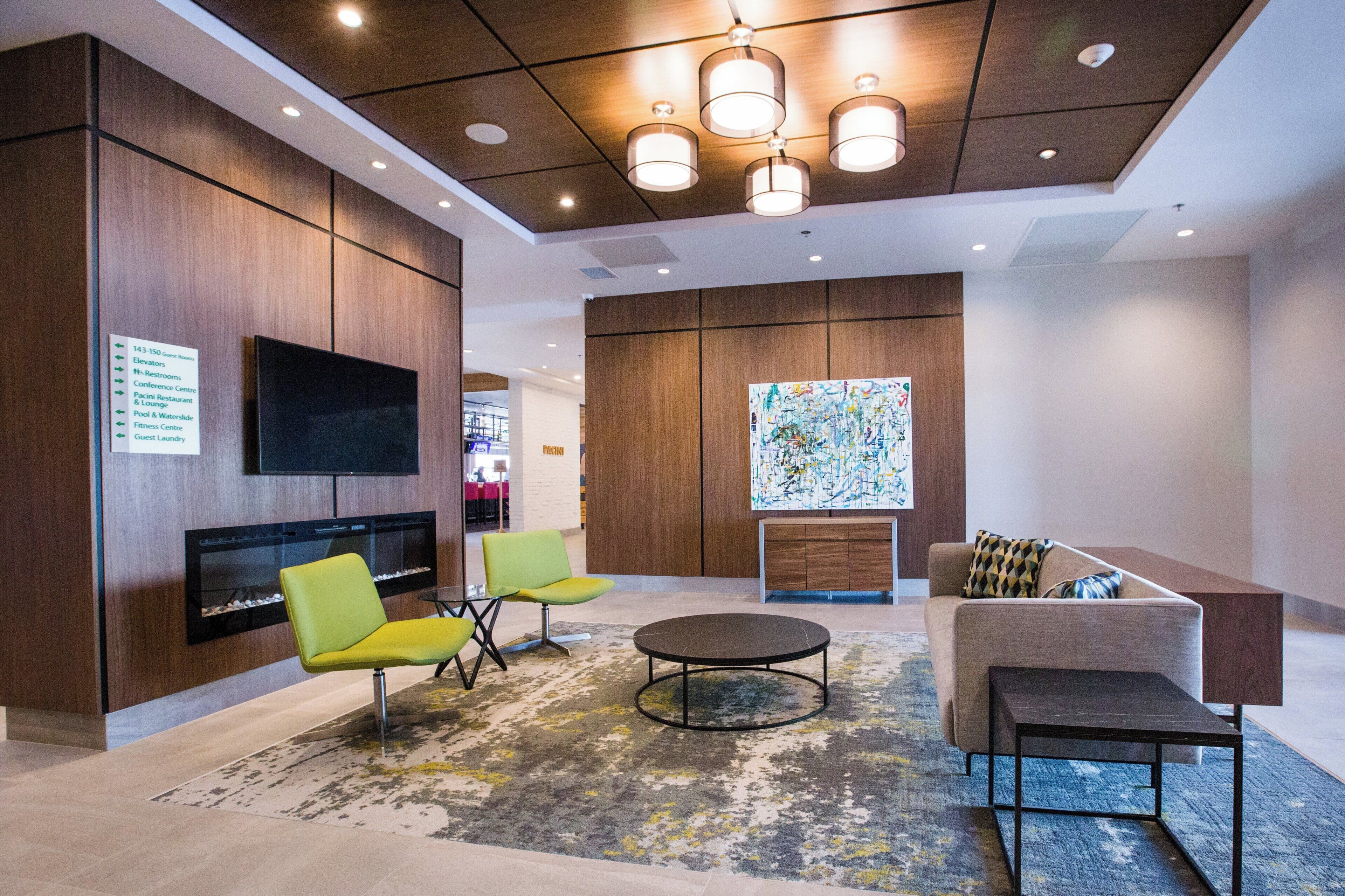A modern lobby with a flat-screen TV, seating area, and a fireplace.