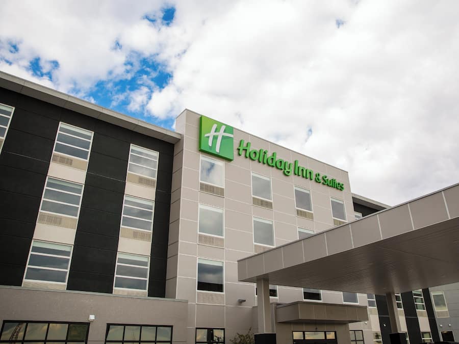 Un hotel Holiday Inn Express con fachada moderna, amplios ventanales y cielo despejado.