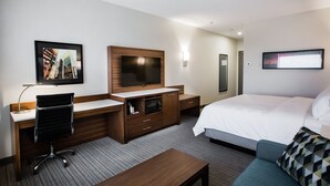 A hotel room with a bed, a desk with a chair, a TV, a microwave, and a large window. - Holiday Inn Calgary South Conference Center by IHG (Calgary)