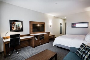 A hotel room with a bed, a desk with a chair, a TV, a microwave, and a large window. - Holiday Inn Calgary South Conference Center by IHG (Calgary)