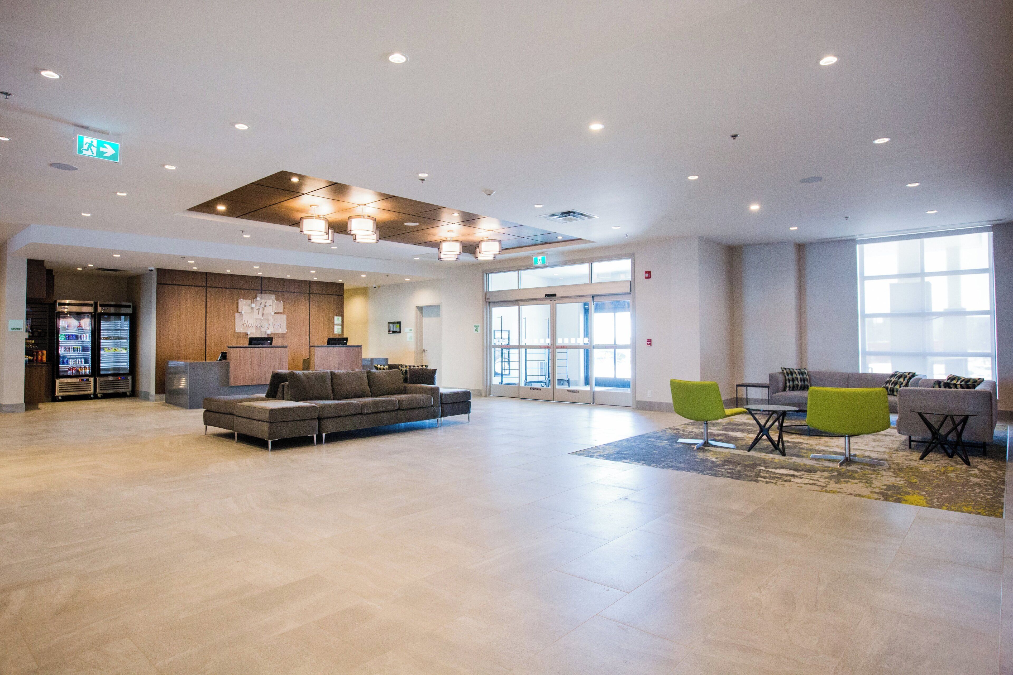 A spacious lobby with a reception desk, seating area, vending machines, and a large window providing natural light.