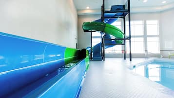 Eine Indoor-Wasserrutsche mit blau-grünen Farbtönen, ein Schwimmbecken und eine Treppe zu einer erhöhten Plattform.