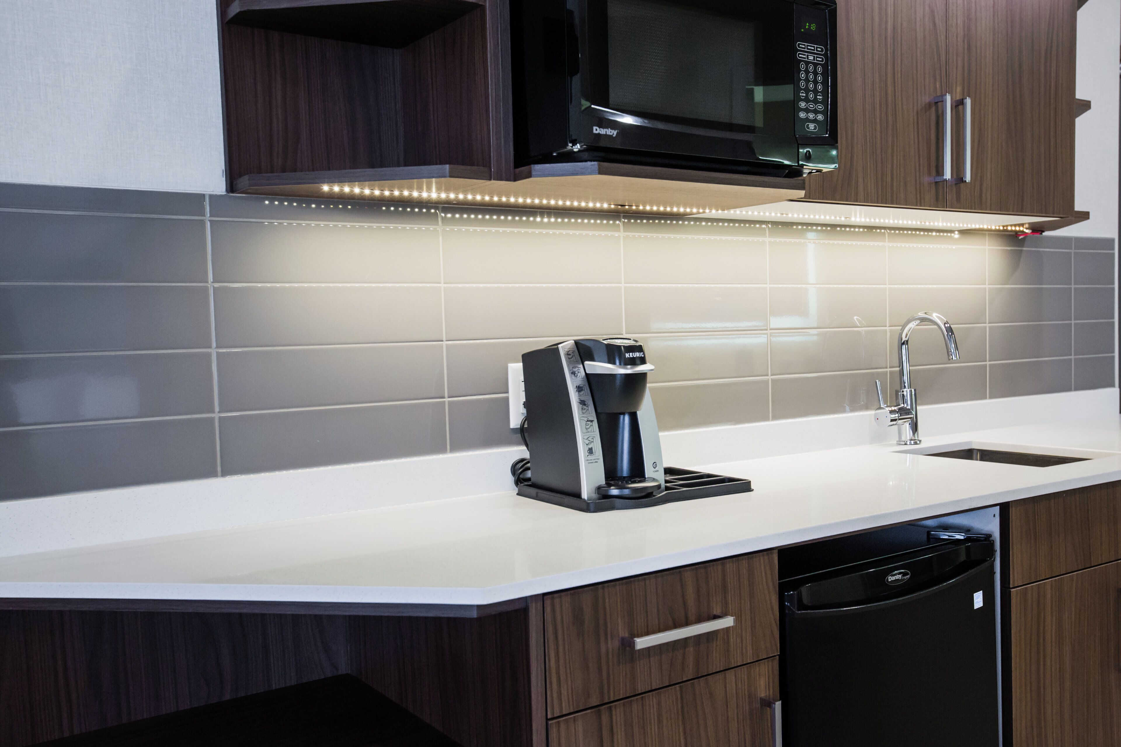 Una cocina moderna con microondas integrado, cafetera y lavavajillas.