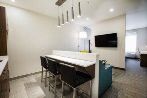 A modern office space with a white desk, black chairs, a teal accent wall, and a flat-screen TV mounted on the wall. - Holiday Inn Calgary South Conference Center by IHG (Calgary)