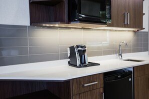 A modern kitchen with a built-in microwave, coffee maker, and dishwasher. - Holiday Inn Calgary South Conference Center by IHG (Calgary)