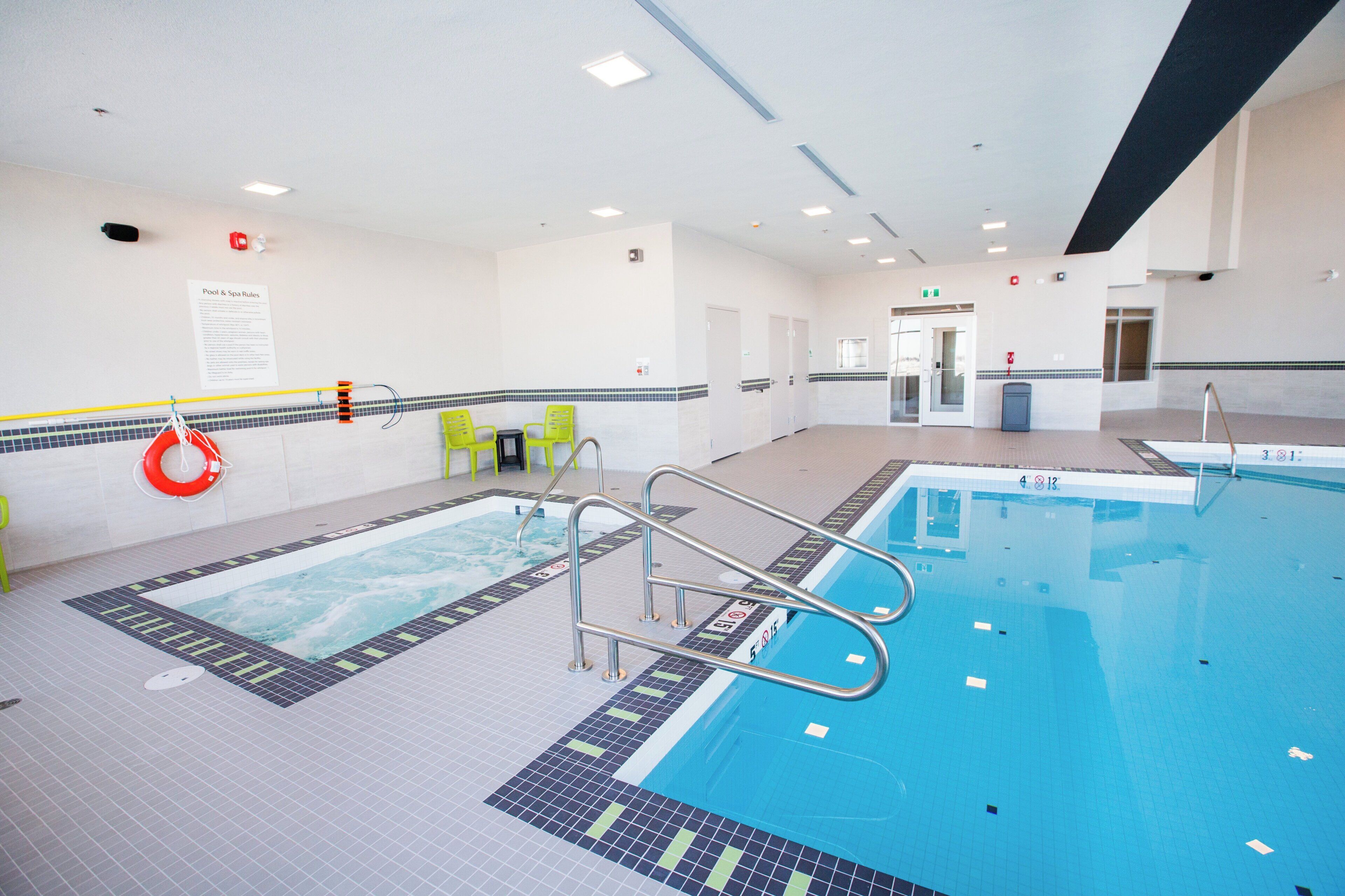 Una piscina interior con carriles claramente delimitados, una silla de socorrista y una zona junto a la piscina con sillas.