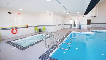 Una piscina interior con carriles claramente delimitados, una silla de socorrista y una zona junto a la piscina con sillas.