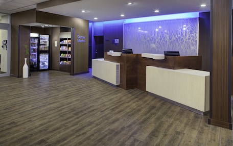 A reception area with a Corner Market refrigerator, a reception desk, and a decorative wall.