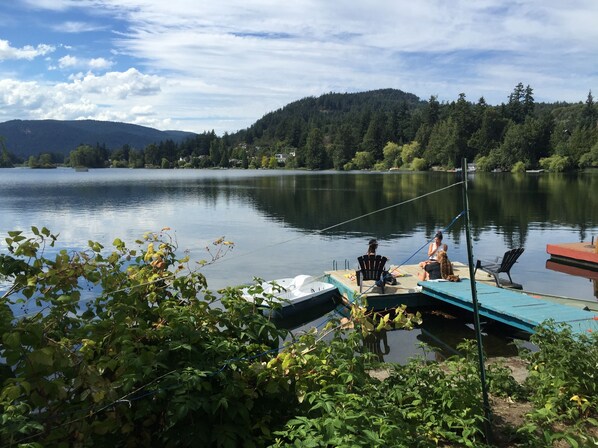 A dock with a fishing rod, a chair, and a small boat. - Leigh Lani Guest House (Victoria)
