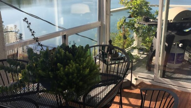 A balcony with a table and chairs, overlooking a lake and forested hills. - Leigh Lani Guest House (Victoria)