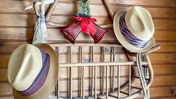 A wooden wall with a hat rack holding three hats and a decorative bell.
