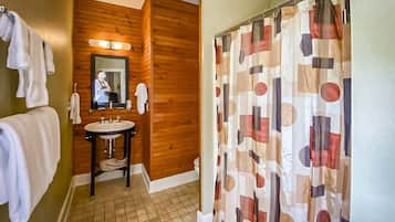 Un baño con tocador de madera, un lavamanos, un espejo y cortina de ducha con diseño geométrico.