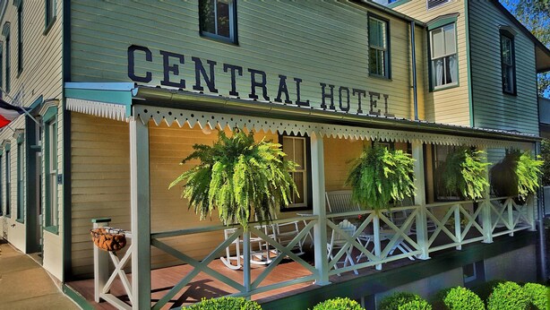 A building labeled "CENTRAL HOTEL" with a porch area featuring outdoor seating and potted plants.
