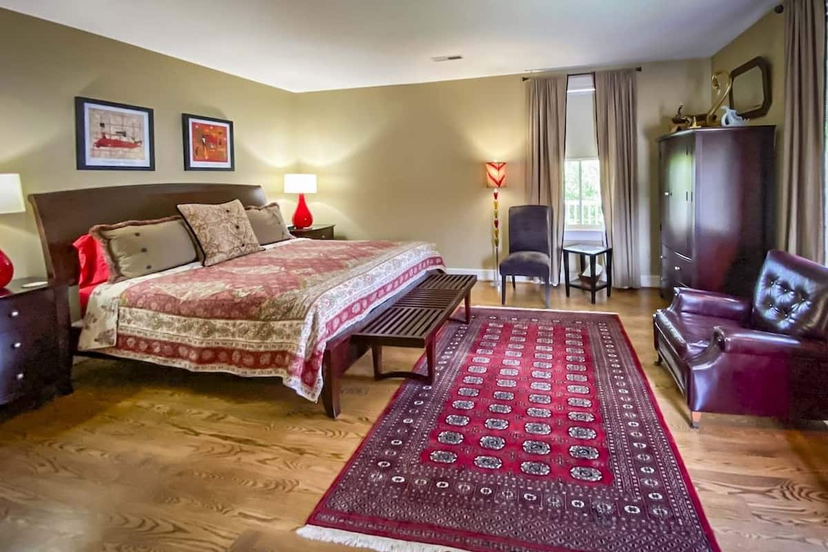 Quarto com uma cama, um banco, uma cadeira, um guarda-roupa e um tapete.